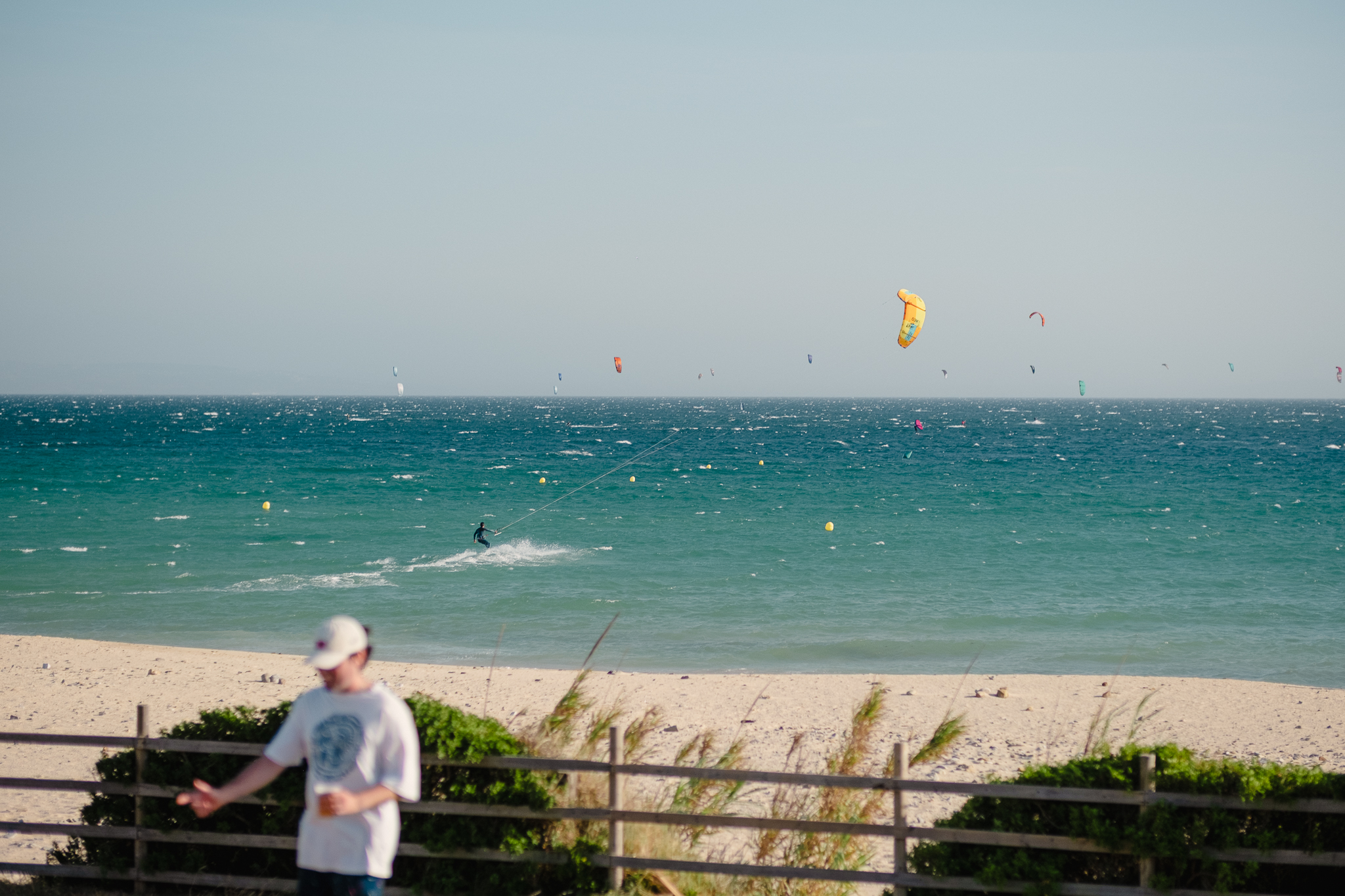Kitesurfers riding in Valdevaqueros Bay, Tarifa, during a windy day with multiple kites across the horizon