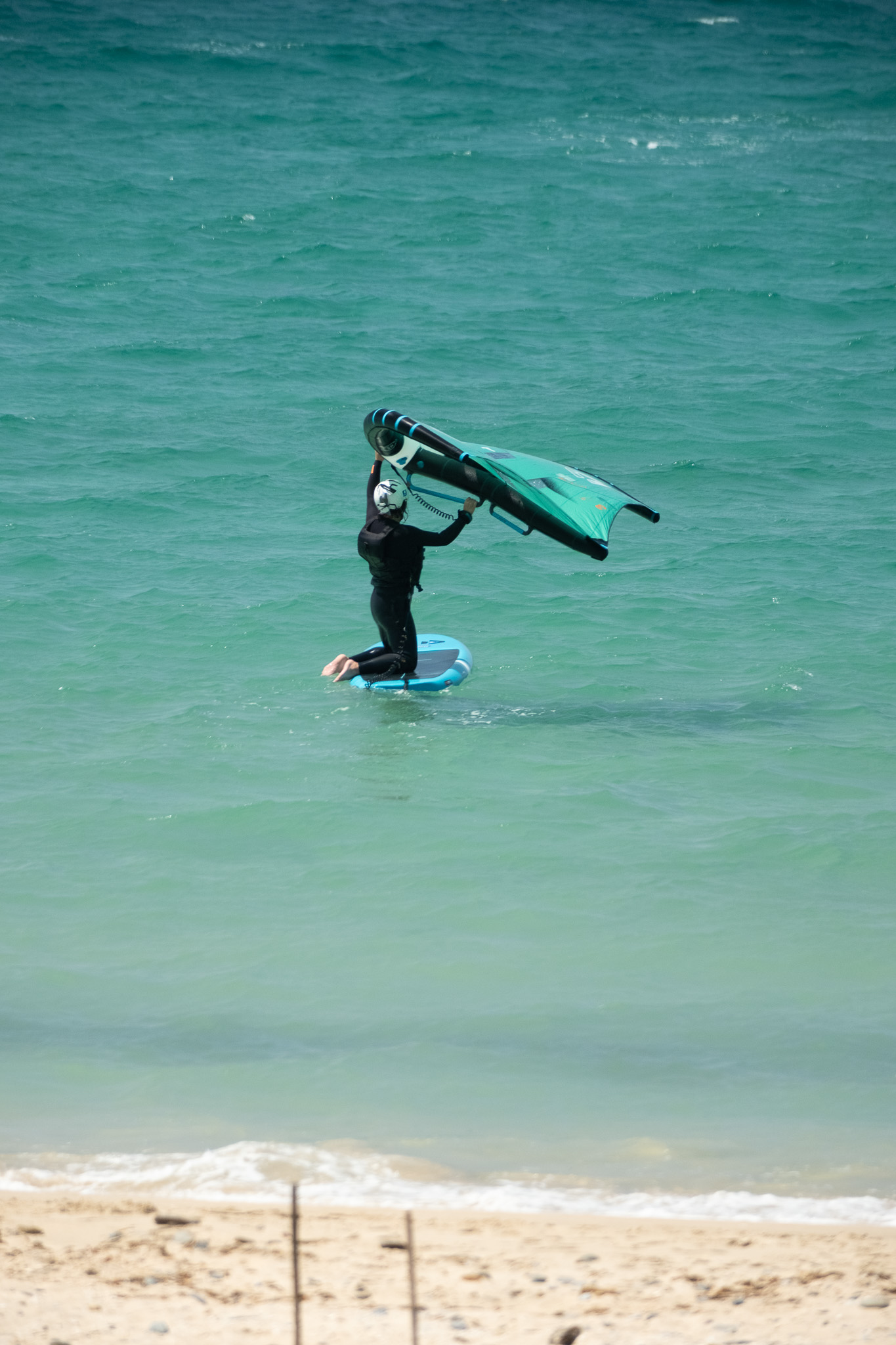 Beginner practising wing control and balance on a board during a wingfoil lesson in Tarifa.