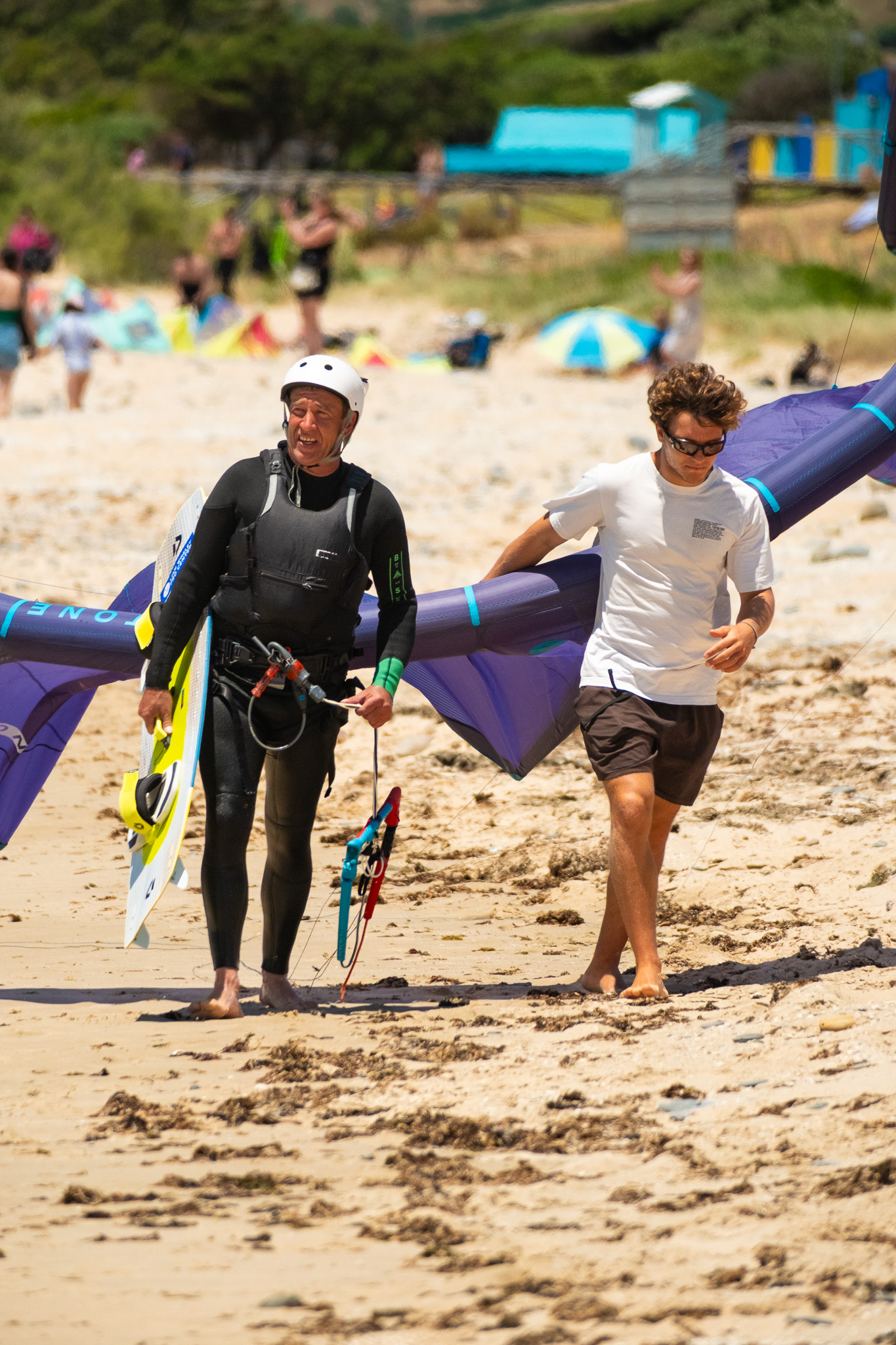 Older kitesurfer carrying a board with an instructor after a lesson at Valdevaqueros Beach in TarifaOlder kitesurfer carrying a board with an instructor after a lesson at Valdevaqueros Beach in Tarifa