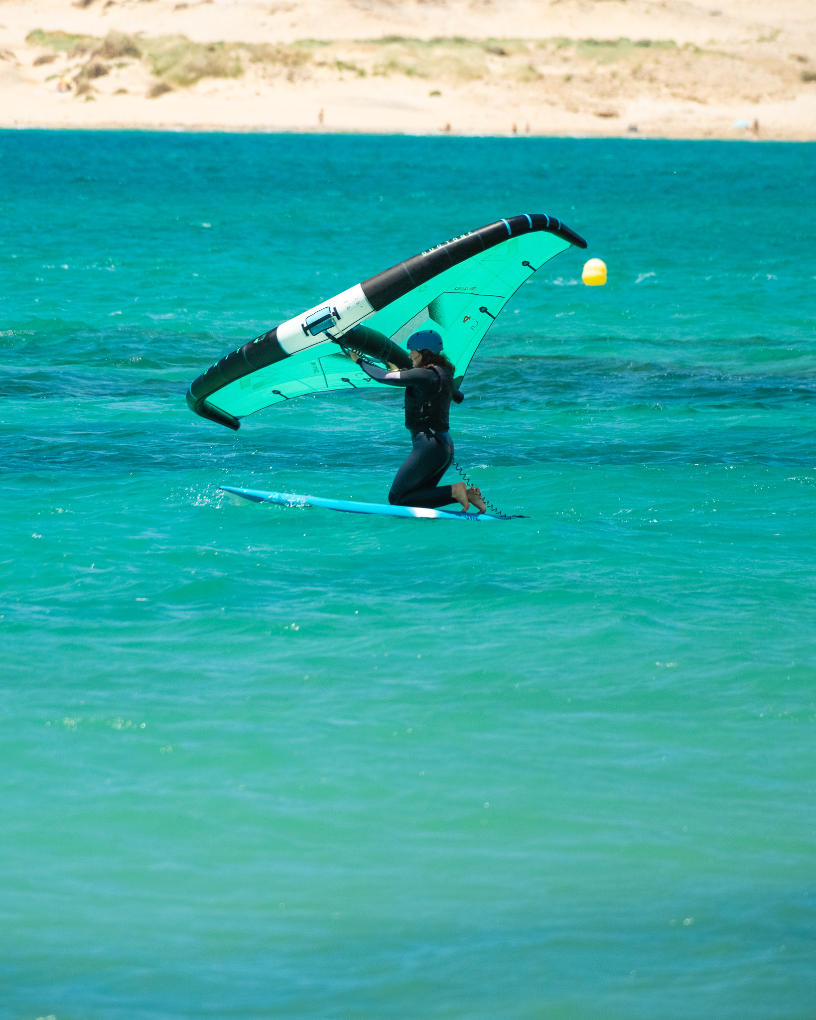 Beginner practising wing control on a large board during a wingfoiling lesson in Tarifa.