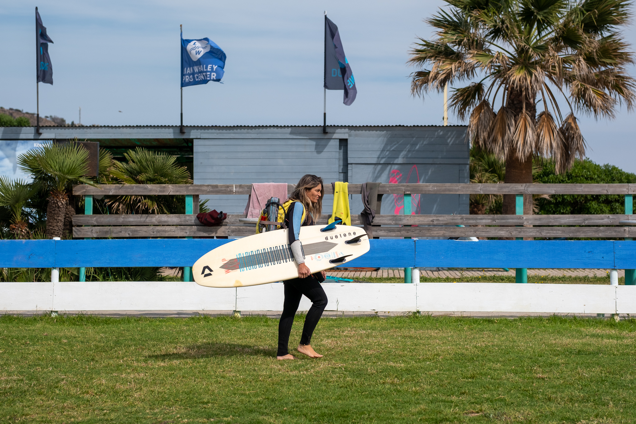 Rider carrying a strapless surfboard outside Liam Whaley Pro Center in Tarifa before a wave-riding session