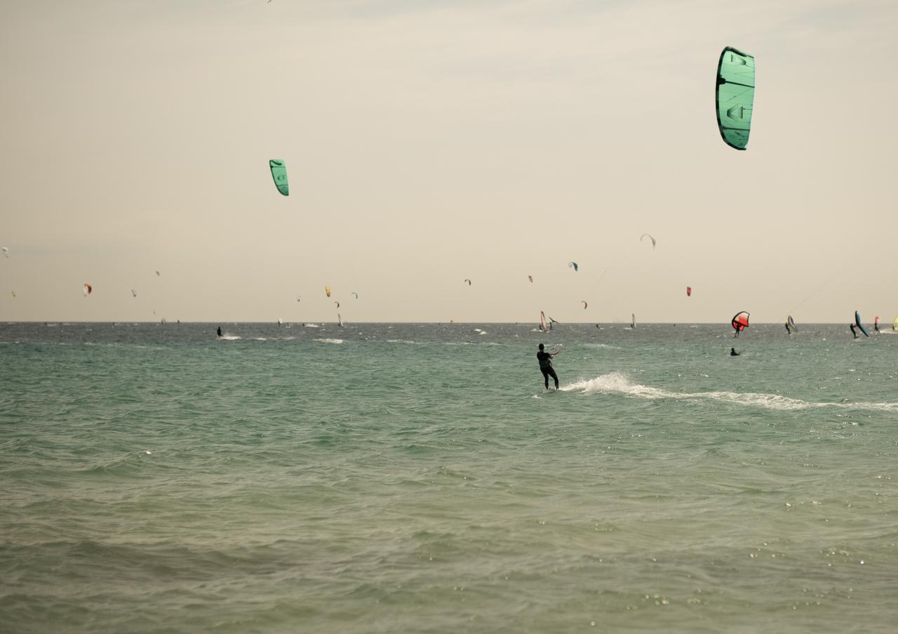 Kitesurfer riding in steady wind at Valdevaqueros Beach in Tarifa with multiple kites on the water.