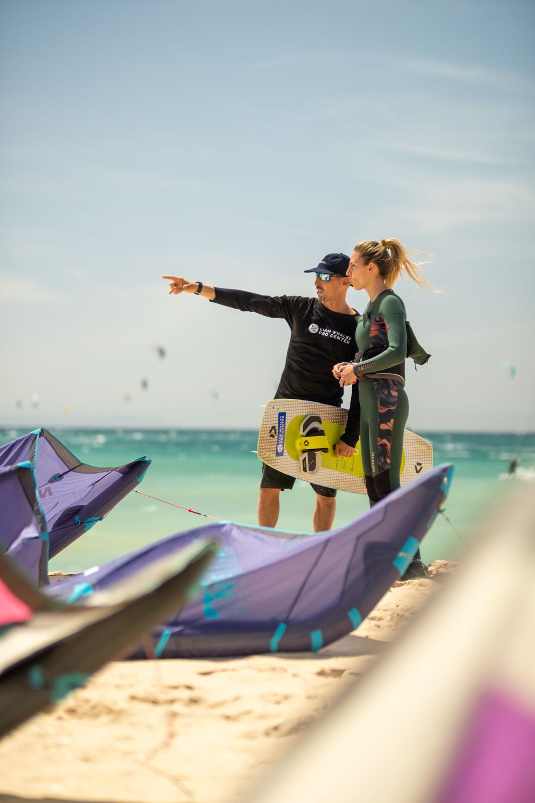 Kitesurf instructor briefing a beginner student on wind direction and beach conditions before a lesson in Tarifa.