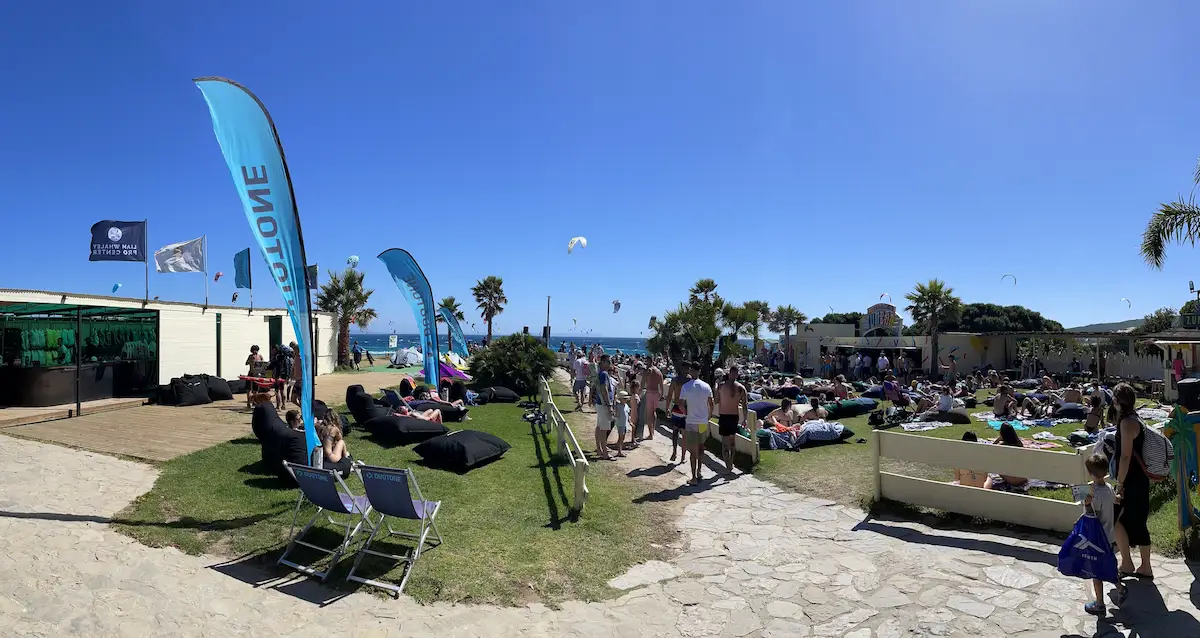 Busy Valdevaqueros beach in Tarifa during peak period with kitesurfers, Duotone flags and social atmosphere