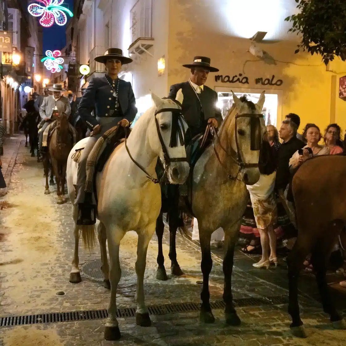 Semana Santa horseback procession moving through crowded streets in Tarifa old town
