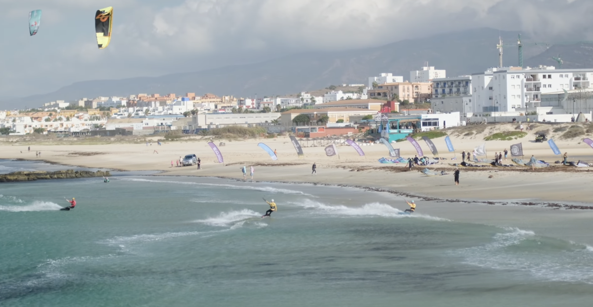 Kitesurfers riding close to shore during competition at Los Lances beach in Tarifa