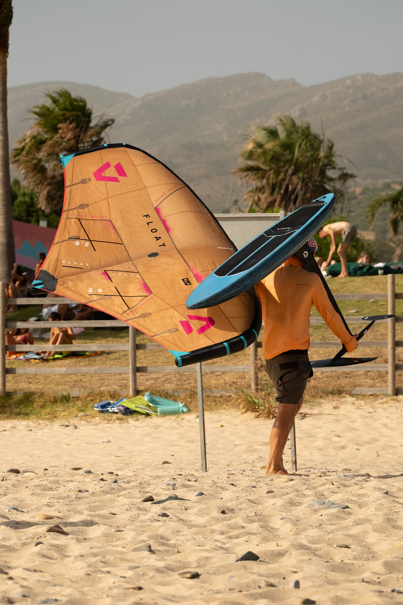 Wingfoil instructor carrying a Duotone wing, foil and board at Valdevaqueros in Tarifa
