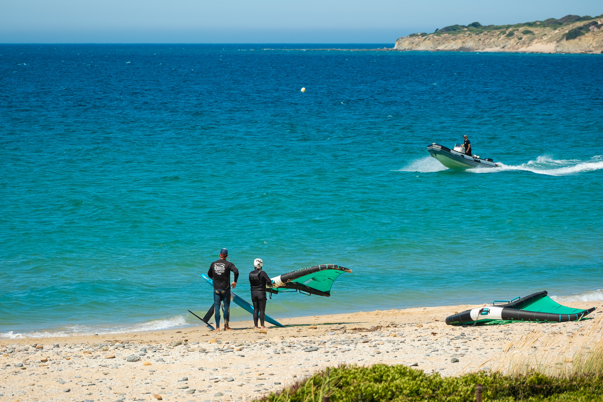Beginner wingfoil lesson at Valdevaqueros Beach with instructor and safety boat in the water