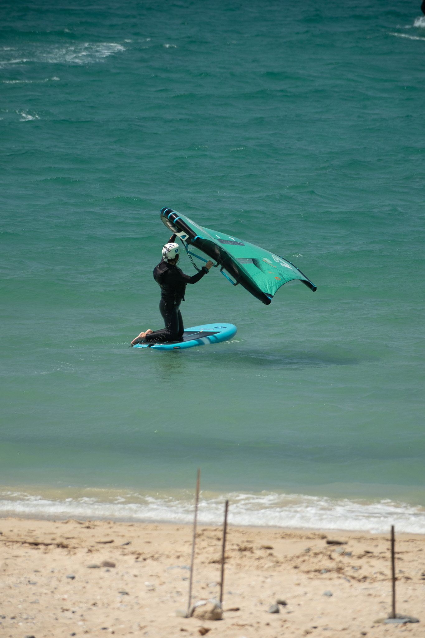 Beginner practising wing control on a stable wingfoil board during a lesson in Tarifa