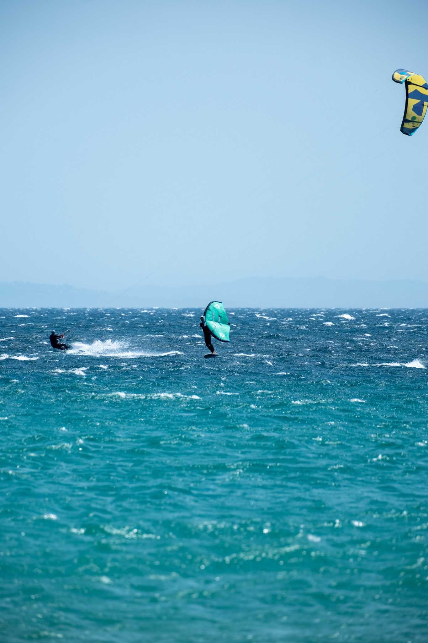 Kitesurfer and wingfoiler riding in windy conditions at Valdevaqueros, Tarifa
